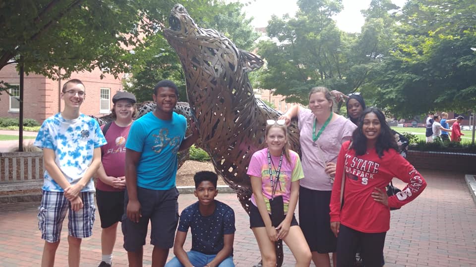 4-H'ers posing in front of wolf sculpture on NC State University Campus. 